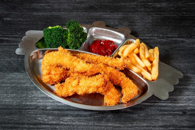 Kids' meal with crispy chicken tenders, french fries, ketchup, and broccoli on a metal tray.